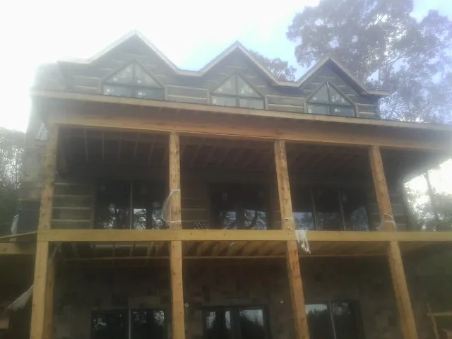 Dormers and porch framing on a large log home under construction — Roof Coating work by our crew in Arkansas City