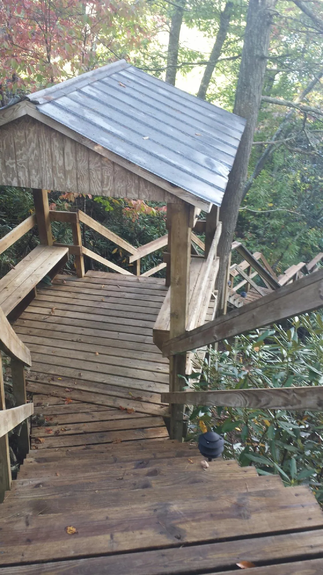 Metal roofed shelter over wooden steps on a wooded walkway — Skylight Repair & Installation work by our crew in Arkansas City