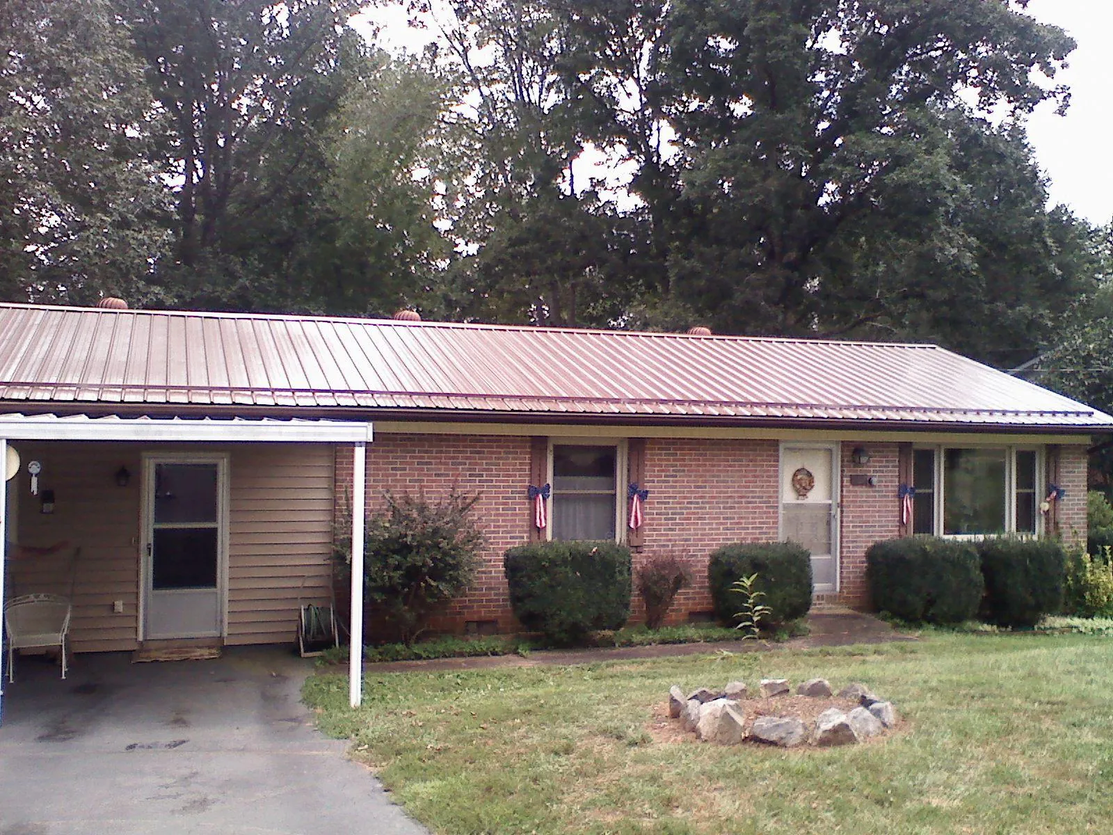 Bronze metal roof and carport on a brick ranch home — Roof Repair work by our crew in Arkansas City