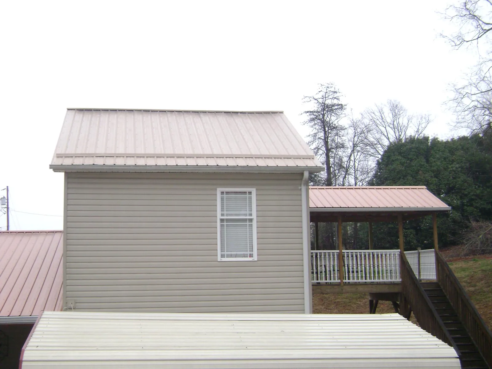 Tan metal roofs on a two story addition and attached porch, from a Roof Replacement job in Arkansas City
