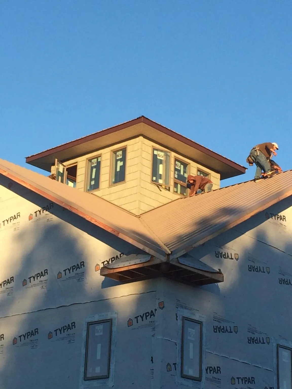 Roofers working around a rooftop cupola on a new metal roof at sunset — Roof Waterproofing in Arkansas City by Roofing Brothers